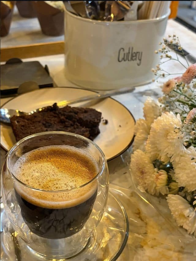 An espresso shot beside a slice of cake